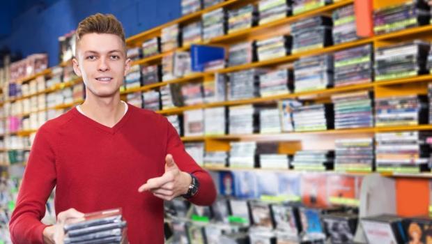 A young man points to a stack of CD jewel cases at a record store.